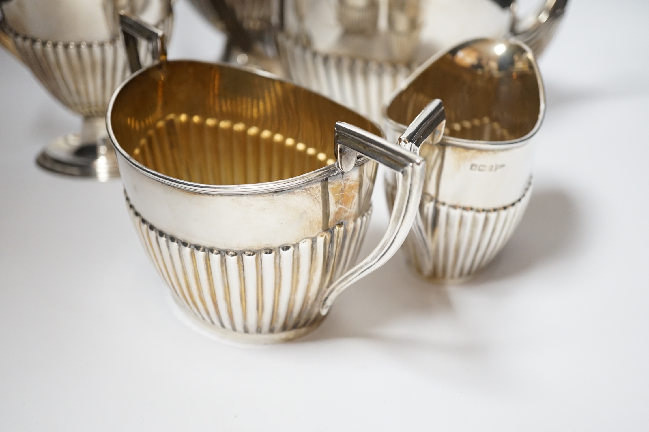 An Edwardian matched demi fluted silver five piece tea and coffee service, by Walker & Hall, Chester, 1906 and Sheffield, 1907/1908, the coffee pot and hot water jug with pedestal foot, gross weight 79.3oz.